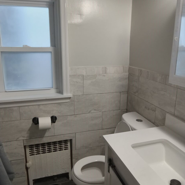 A bathroom with a window, sink, and mirror.