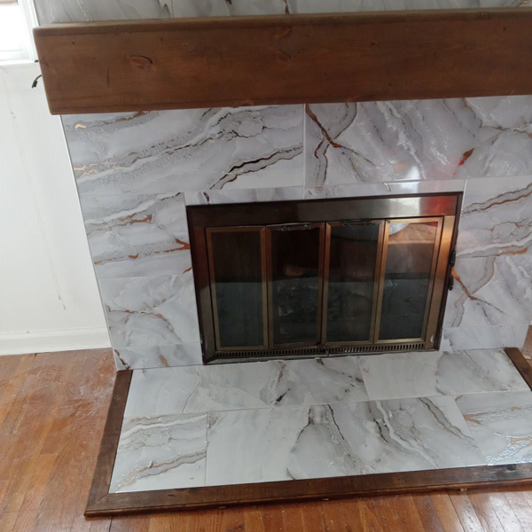 A cozy fireplace with elegant marble tiles and wooden trim, creating a warm and inviting ambiance.